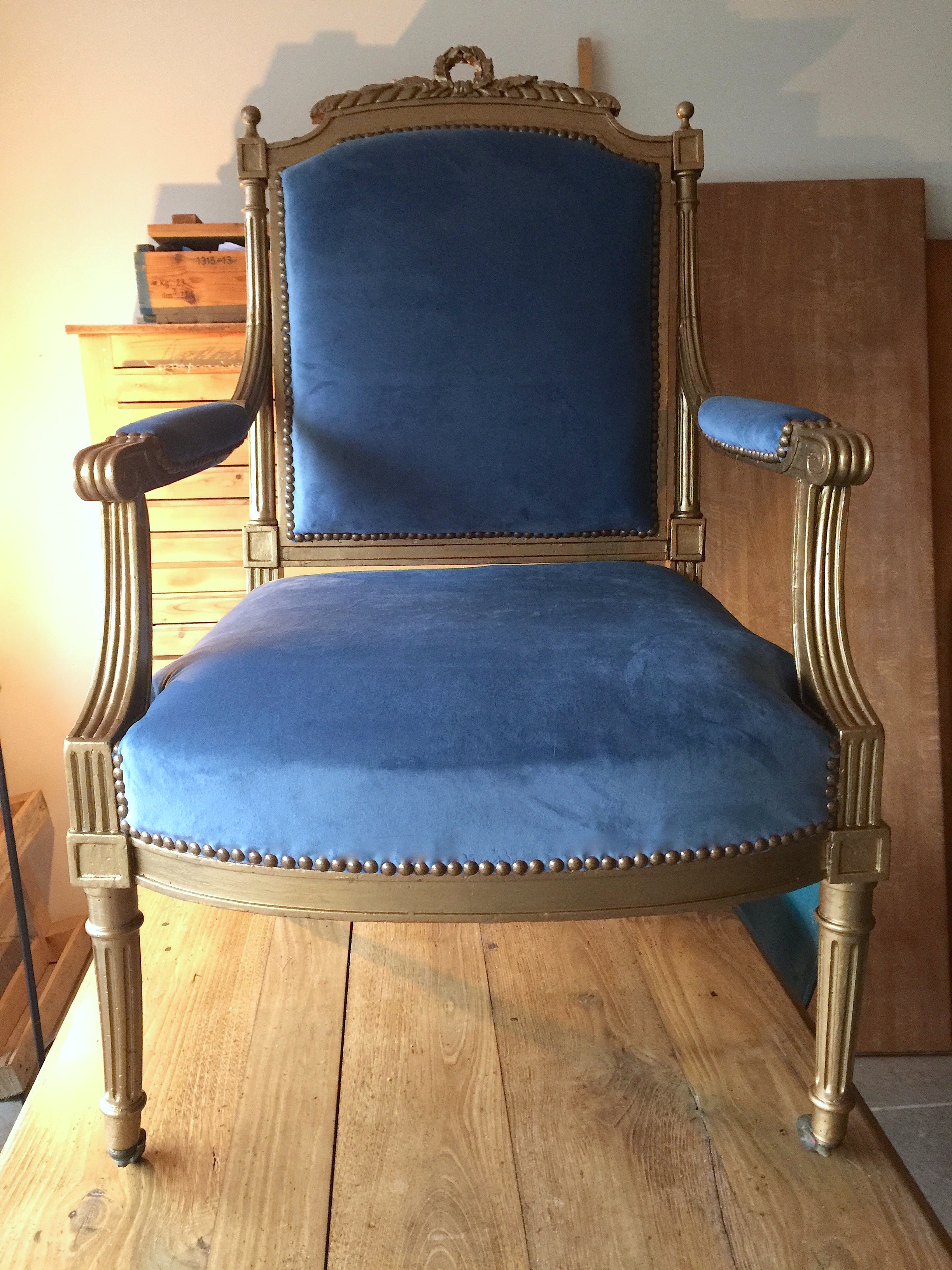 Fauteuil Napoléon III après réparation. Tapisserie d'ameublement bleu. Peinture or. Atelier artisanal.